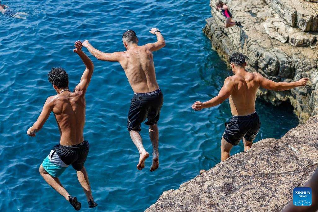 People dive into the sea to cool off from the cliff at the Seagull's Rocks Beach in Pula, Croatia on Aug. 14, 2024. The maximum temperature in Pula reaches 35 degrees Celsius during the day. (Photo: Xinhua)