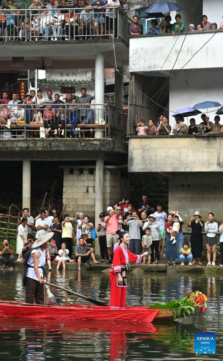 People watch an outdoor performance in Wangdong Township of Rongshui Miao Autonomous County in south China's Guangxi Zhuang Autonomous Region, Aug. 18, 2024. In recent years, Wangdong Township has leveraged its abundant water resources to promote rural vitalization. Supported by the pairing assistance from Lianjiang City in Guangdong Province, the township has organized water sports competitions, mountain song duets, and activities under the theme of intangible cultural heritage in schools. These initiatives aim to build a water culture brand and advance the development of ethnic cultural tourism. Photo: Xinhua