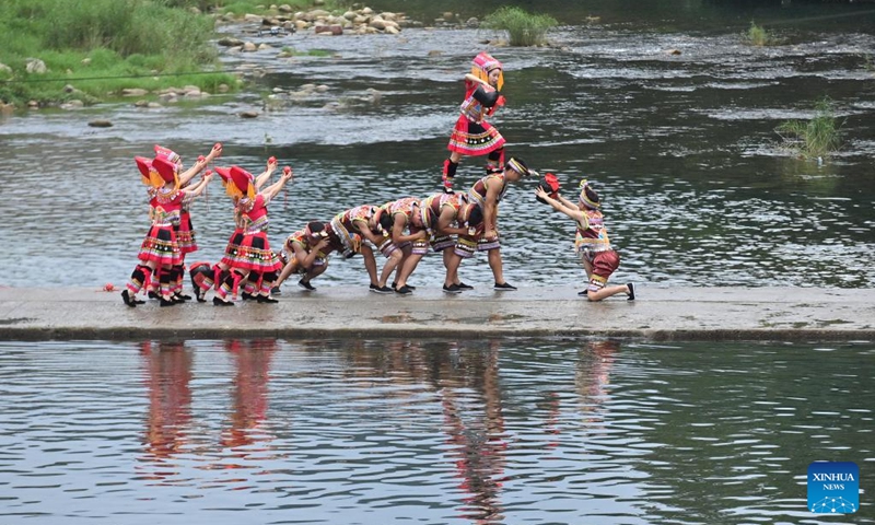 Villagers perform on a stone pathway over a river in Wangdong Township of Rongshui Miao Autonomous County in south China's Guangxi Zhuang Autonomous Region, Aug. 18, 2024. In recent years, Wangdong Township has leveraged its abundant water resources to promote rural vitalization. Supported by the pairing assistance from Lianjiang City in Guangdong Province, the township has organized water sports competitions, mountain song duets, and activities under the theme of intangible cultural heritage in schools. These initiatives aim to build a water culture brand and advance the development of ethnic cultural tourism. Photo: Xinhua