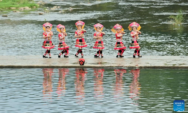 Villagers dance on a stone pathway over a river in Wangdong Township of Rongshui Miao Autonomous County in south China's Guangxi Zhuang Autonomous Region, Aug. 18, 2024. In recent years, Wangdong Township has leveraged its abundant water resources to promote rural vitalization. Supported by the pairing assistance from Lianjiang City in Guangdong Province, the township has organized water sports competitions, mountain song duets, and activities under the theme of intangible cultural heritage in schools. These initiatives aim to build a water culture brand and advance the development of ethnic cultural tourism.  Photo: Xinhua