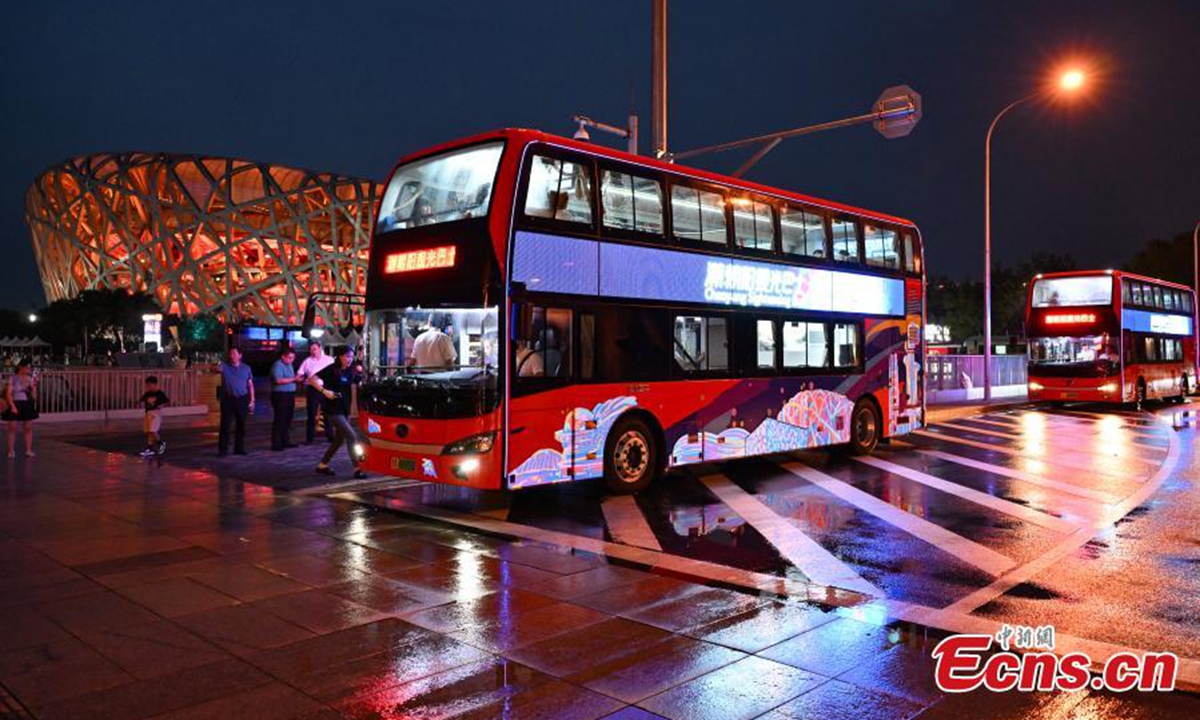 A sightseeing bus stops in front of the iconic Bird's Nest stadium or National Stadium in Beijing,<strong></strong> Aug. 18, 2024. The Trendy Chaoyang (Bird's Nest-Liangma River Pier) night tour will be launched in Beijing. The 17-kilometer bus tour route allows tourists to enjoy the beautiful night views of Chaoyang's landmark tourist sites including the Bird's Nest, the Water Cube, the Beijing Olympic Tower, the China Science and Technology Museum, the China Arts and Crafts Museum, the China Intangible Cultural Heritage Museum, the Communist Party of China History Exhibition Hall and the Liangma River International Style Waterfront, etc. in an hour trip.
 Photo: China News Service