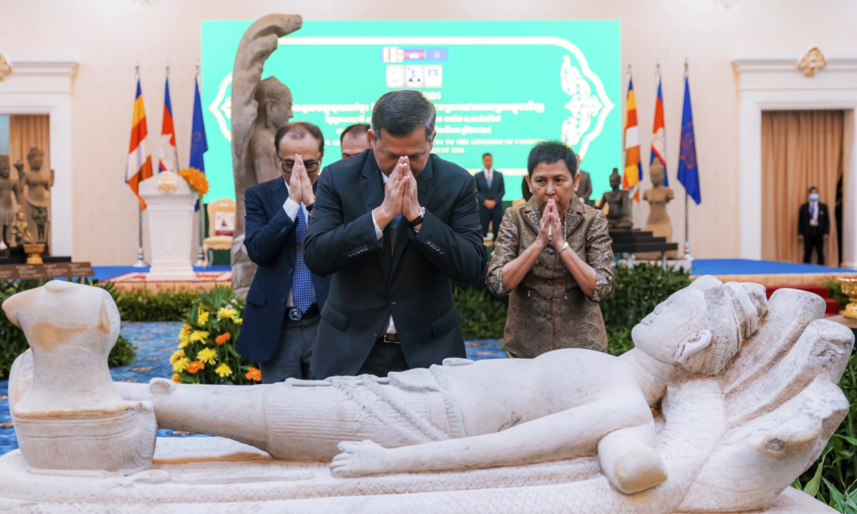 Cambodian Prime Minister Hun Manet (center), prays before a statue with Minister of Culture and Fine Arts Phoeurng Sackona (right), during a ceremony for the return of artifacts in Peace Palace in Phnom Penh, Cambodia on August 22, 2024. On the day, Hun Manet led a celebration for the return of dozens of precious artifacts from museums and private collectors abroad, and said his government will continue working to bring more home. Photo: VCG