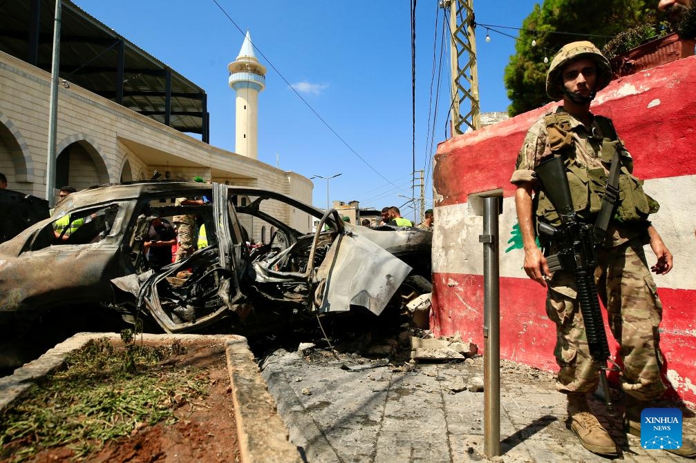 A soldier stands guard near a vehicle destroyed by missiles from an Israeli drone in Sidon, Lebanon, on Aug. 21, 2024. An Israeli drone fired two air-to-surface missiles at a civilian SUV at the southern entrance to the city of Sidon on Wednesday morning, killing a leader in the Al-Aqsa Martyrs Brigades, the armed wing of the Palestinian National Liberation Movement (Fatah), Lebanese military sources told Xinhua.  (Photo: Xinhua)