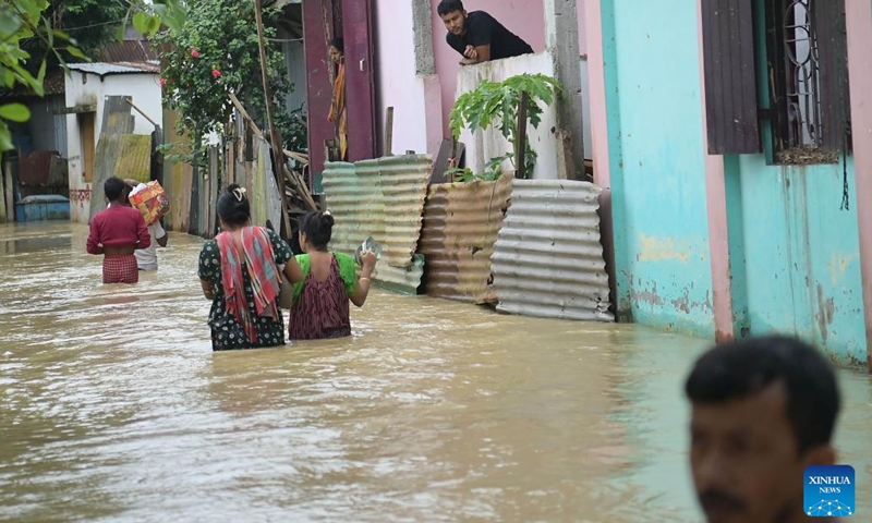 People wade through a flooded street on the outskirts of Agartala, the capital city of India's northeastern state of Tripura on Aug. 20, 2024. (Photo: Xinhua)