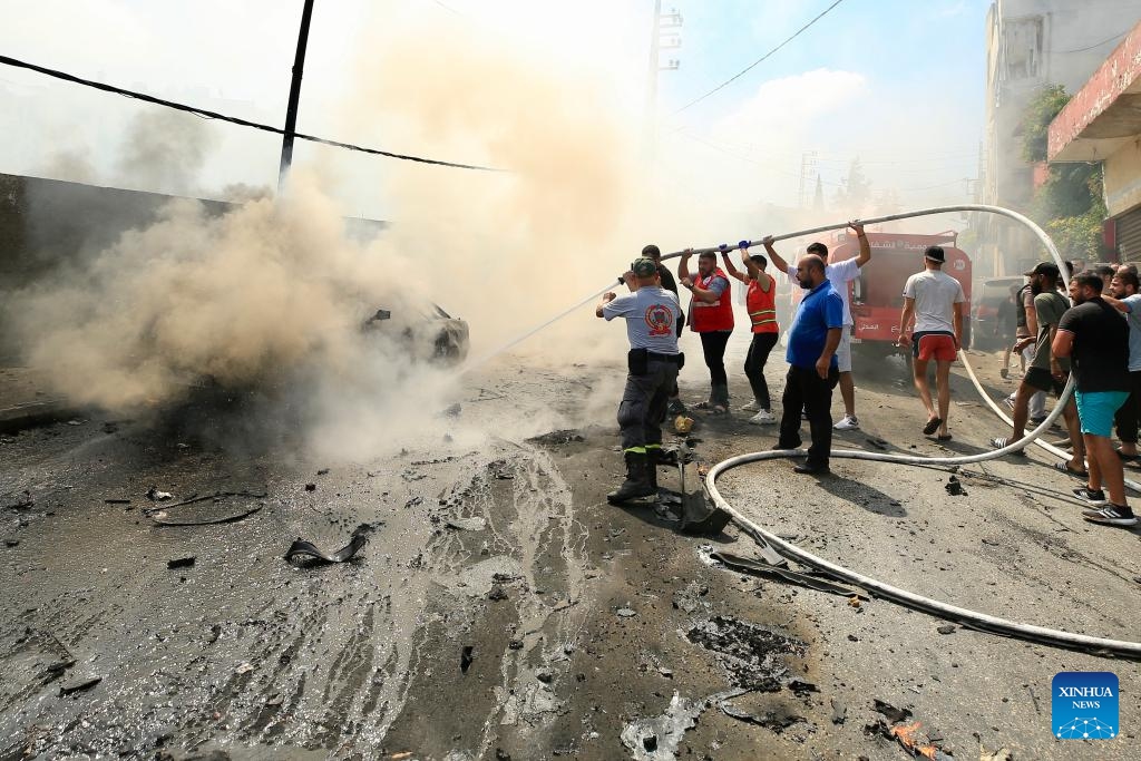 People try to extinguish a fire on a vehicle hit by missiles from an Israeli drone in Sidon, Lebanon, on Aug. 21, 2024. An Israeli drone fired two air-to-surface missiles at a civilian SUV at the southern entrance to the city of Sidon on Wednesday morning, killing a leader in the Al-Aqsa Martyrs Brigades, the armed wing of the Palestinian National Liberation Movement (Fatah), Lebanese military sources told Xinhua. (Photo: Xinhua)