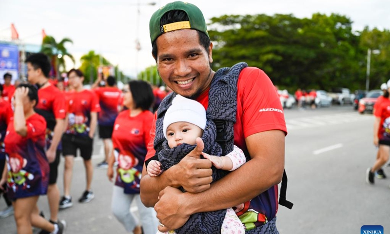 A man holding a baby participates in the Malaysia-China 2024 friendship run in Kota Kinabalu, Sabah, Malaysia, Aug. 25, 2024. Over 5,000 participants joined the Malaysia-China 2024 friendship run in Kota Kinabalu, Sabah, Malaysia on Sunday, expanding an annual event that celebrates the 50th anniversary of the establishment of bilateral ties. (Xinhua/Cheng Yiheng)