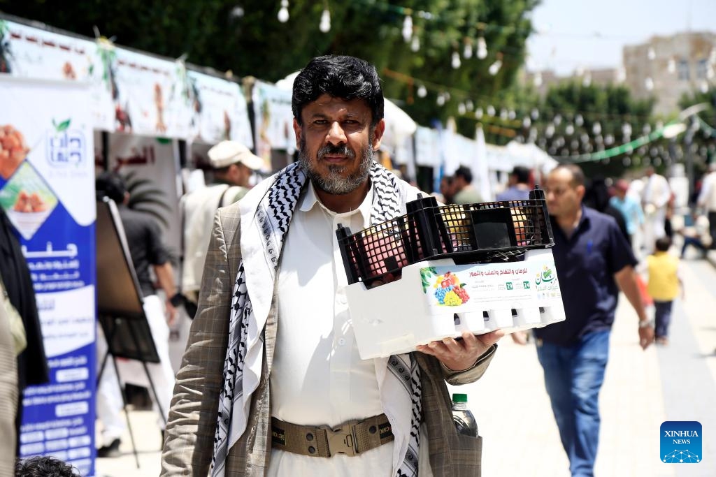 A customer carries a box of pomegranates at a fruit festival in Sanaa, Yemen, Aug. 25, 2024. The week-long fruit festival kicked off here Saturday. (Photo: Xinhua)