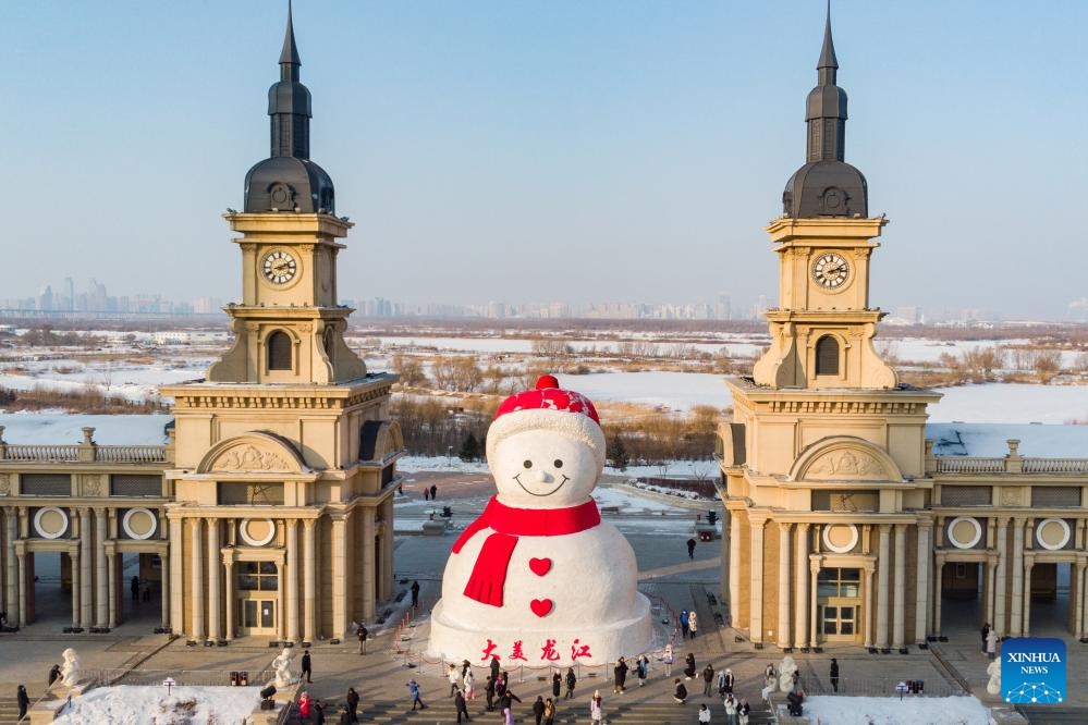 A drone photo taken on Jan. 5, 2024 shows tourists having fun in front of a giant snowman near the Songhua River in Harbin, northeast China's Heilongjiang Province. Known as China's Ice City, Harbin has a reputation for its cool weather and diversified attractions, even during the summer months, which helps it remain attractive to tourists throughout the year. (Photo: Xinhua)