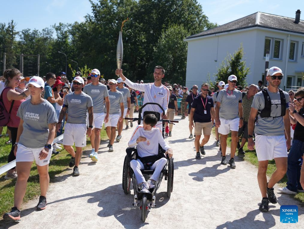 Torch bearer Valentin Francavilla (C rear) holds the torch along with his brother Theophile Francavilla (C front) during the Paris 2024 Paralympic Games Torch Relay in Fontainebleau, France, Aug. 27, 2024. (Photo: Xinhua)