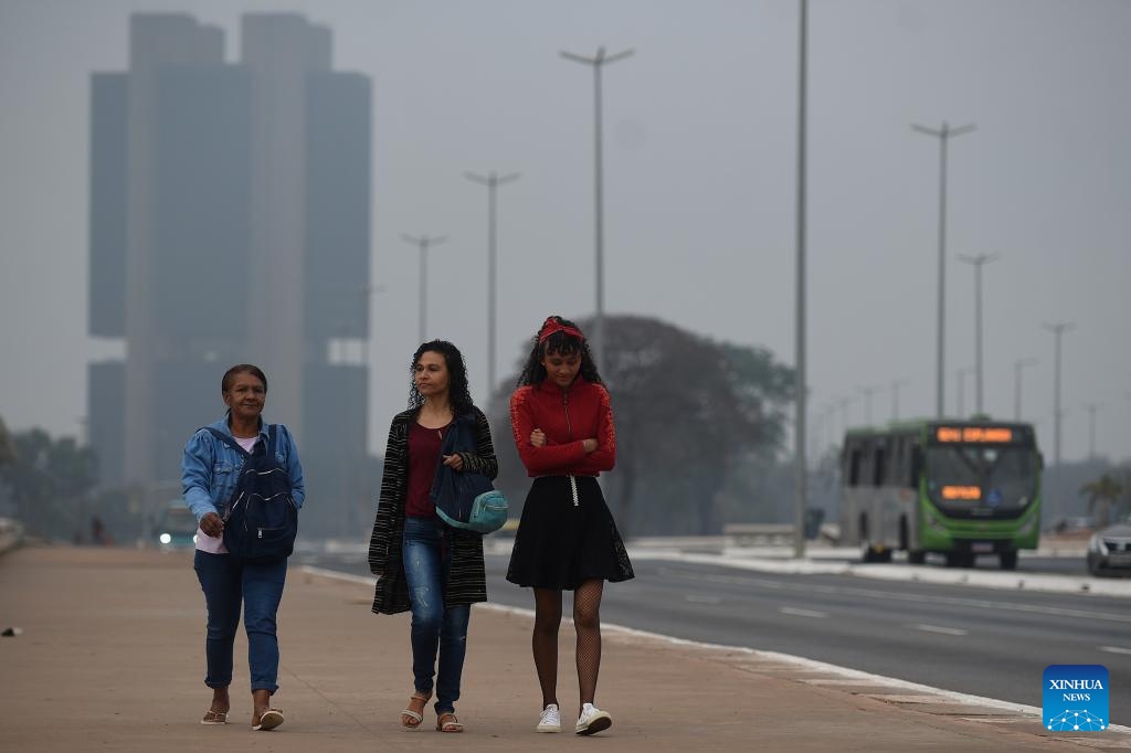 People walk on the street as the Central Bank headquarters building is covered by smoke in Brasilia, Brazil, Aug. 26, 2024. (Photo: Xinhua)