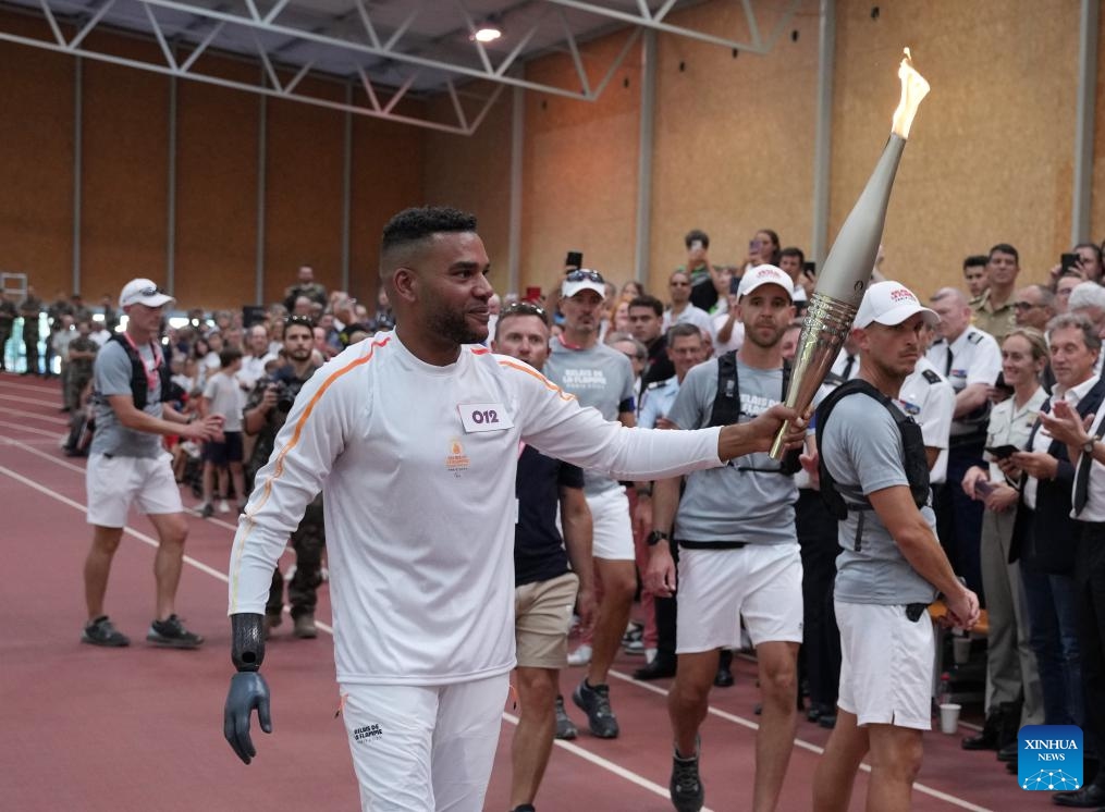 Torch bearer Alain Akakpo (front) holds the torch during the Paris 2024 Paralympic Games Torch Relay in Fontainebleau, France, Aug. 27, 2024. (Photo: Xinhua)