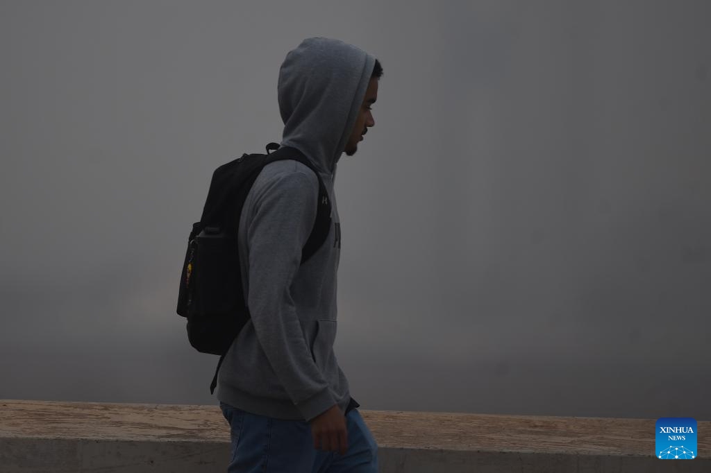 A man walks on the street as the National Congress building is covered by smoke in Brasilia, Brazil, Aug. 26, 2024. (Photo: Xinhua)