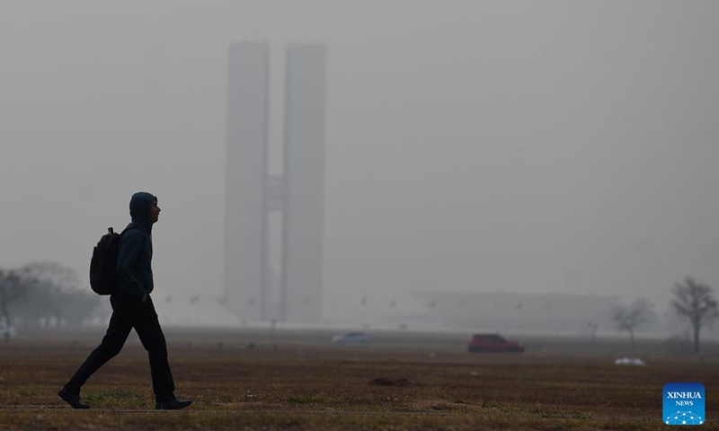 A man walks on the street as the National Congress building is covered by smoke in Brasilia, Brazil, Aug. 26, 2024. (Photo: Xinhua)