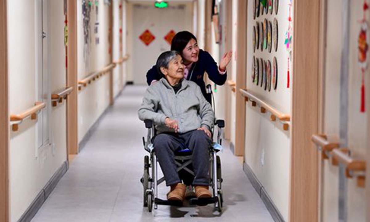 A young female caretaker attends to an old lady at an elder care facility in Shenyang, Northeast China's Liaoning Province, on Friday. Photo: VCG