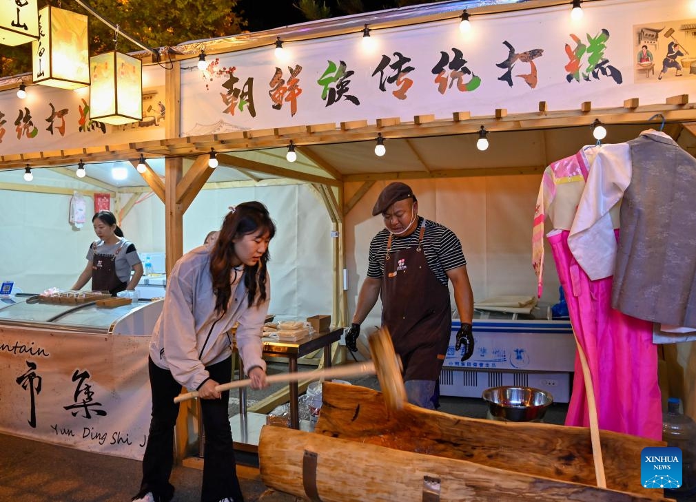 A tourist experiences making glutinous rice cake at the Yunding market in Erdaobaihe Township of Antu County in Yanbian Korean Autonomous Prefecture, northeast China's Jilin Province, June 13, 2024. In recent years, while the booming night economy in China's northeast region is providing local people and tourists with colorful nightlife options, it has given impetus to the growth of local economy. (Photo: Xinhua)