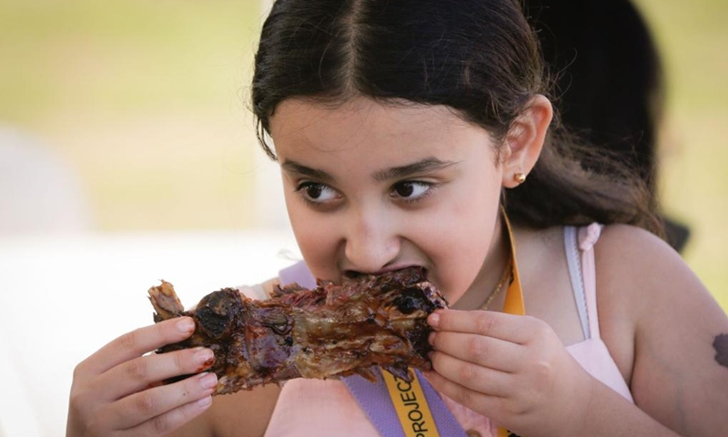 A girl takes a bite of grilled ribs at the Halal Ribfest event in Surrey, British Columbia, Canada, Aug. 30, 2024. The event runs from Aug. 30 to Sept. 1. Photo: Xinhua