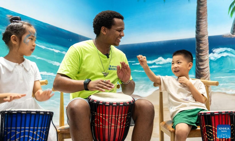 A volunteer plays African drum with children during a hands-on experience session at the Angola pavilion of a permanent exhibition hall of the China-Africa Economic and Trade Cooperation Promotion Innovation Demonstration Park in Changsha, central China's Hunan Province, Aug. 30, 2024. Various activities promoting youth communication between China and Africa were organized here during the summer vacation. With the help of African volunteers from local universities, Chinese students were able to feel the charm of African culture by learning traditional African dance, music, folk arts, and making immersive tours of African customs via VR devices. Photo: Xinhua