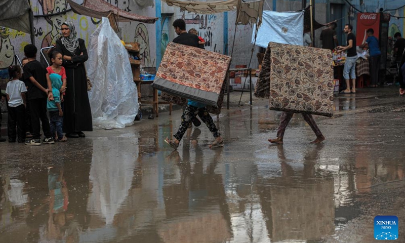 Displaced children walk in the rain at a school in Deir al-Balah, central Gaza Strip, Sept. 1, 2024. (Photo: Xinhua)