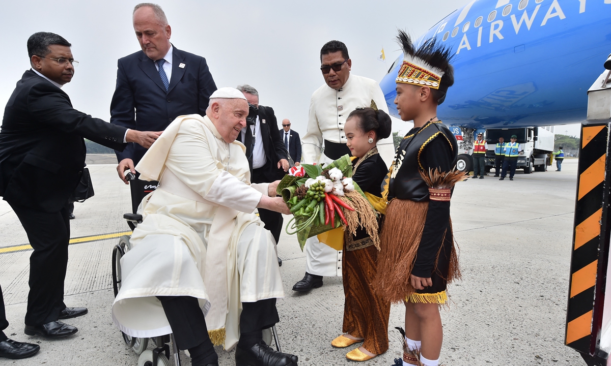 Pope Francis received a bouquet of flowers from two traditionally dressed children upon his arrival in Jakarta, Indonesia on September 3, 2024. Photo: AFP