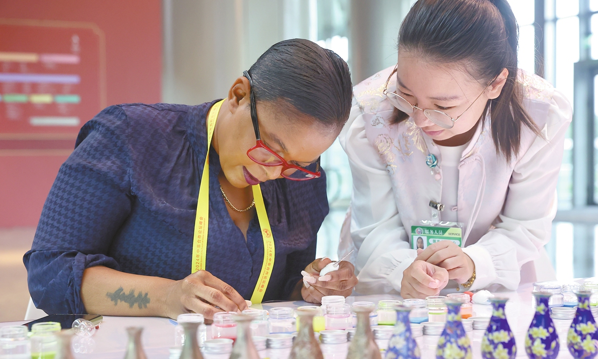 An African journalist experiences the craft of making Jingtailan in an interactive display area of Chinese intangible cultural heritages at the press center of the 2024 Summit of the Forum on China-Africa Cooperation on September 4, 2024, in Beijing. Jingtailan represents a special localized cloisonne wrought of copper and porcelain. Photo: VCG