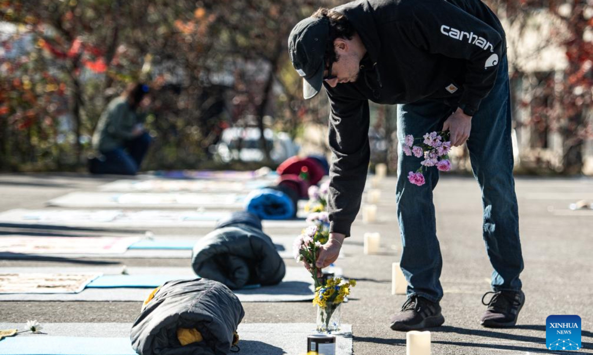 A man places a flower on memorial of a Lewiston Shooting victim in Lewiston, Maine, the United States on Oct. 25, 2024. This Friday marks the one year anniversary of the mass shooting in Lewison back in 2023. As many as 18 people were killed and 13 injured in the mass shooting. (Photo: Xinhua)