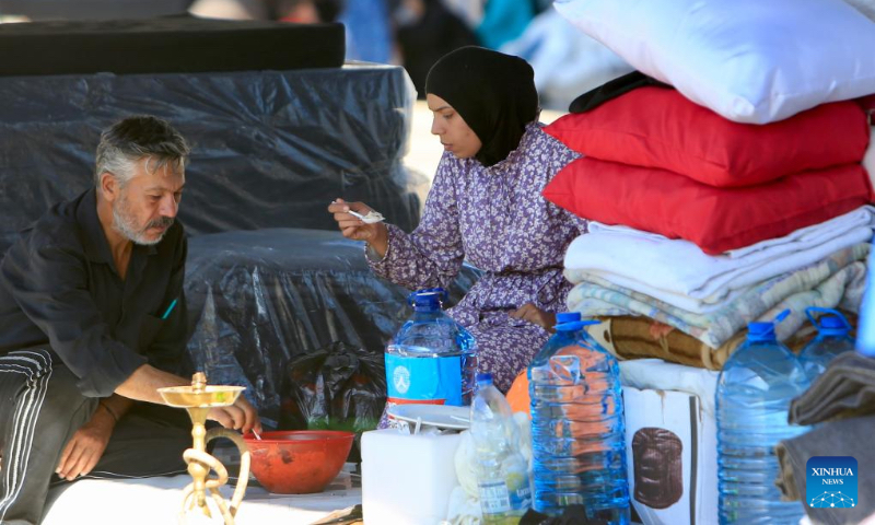 Displaced people have a meal as they live at a parking lot in Sidon, Lebanon on Oct. 3, 2024. (Photo by Ali Hashisho/Xinhua)