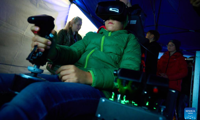 A teen plays a fighter aircraft simulator at the 13th Night at the Institute of Aviation in Warsaw, Poland on Oct. 4, 2024. This annual event, hosted by the Warsaw Institute of Aviation, is one of the largest educational night activities in the country, aimed at promoting knowledge and careers in aviation and engineering. (Photo by Jaap Arriens/Xinhua)