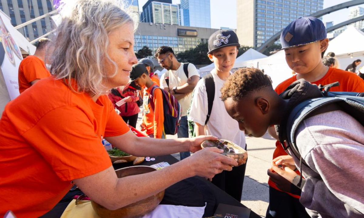 A volunteer (L) introduces the knowledge of smudging to students during an event marking the National Day for Truth and Reconciliation in Toronto, Canada, Sep 30, 2024. Photo:Xinhua