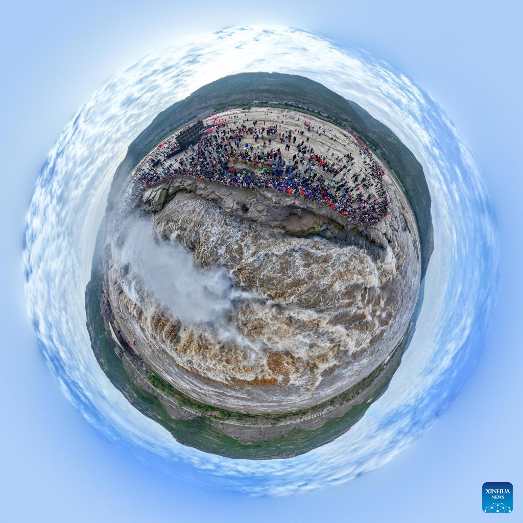 An aerial panoramic drone photo taken on Oct. 4, 2024 shows tourists visiting the Hukou Waterfall on the Yellow River, on the border area between north China's Shanxi and northwest China's Shaanxi provinces. (Xinhua/Chen Yehua)