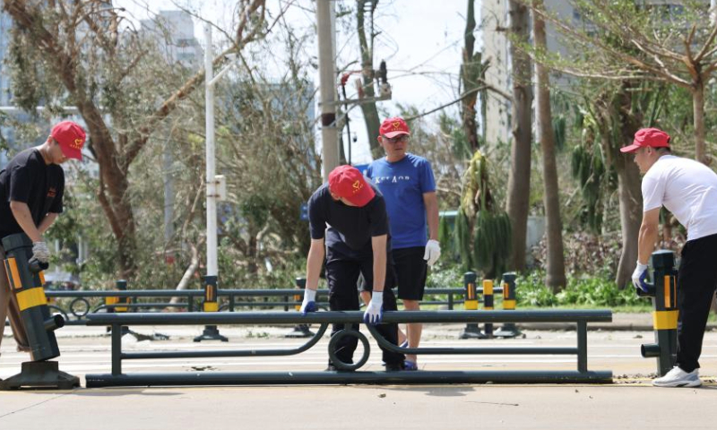 Volunteers lift up a fallen railing on a road in Haikou, south China's Hainan Province, Sept. 8, 2024. Yagi, the 11th typhoon of the year, made landfall in Hainan on Friday afternoon. As winds and rainfall subsided, Hainan downgraded its typhoon alert and initiated swift recovery operations across the province. (Xinhua/Zhang Liyun)