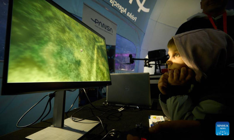 A boy looks at a flight simulator on a monitor at the 13th Night at the Institute of Aviation in Warsaw, Poland on Oct. 4, 2024. This annual event, hosted by the Warsaw Institute of Aviation, is one of the largest educational night activities in the country, aimed at promoting knowledge and careers in aviation and engineering. (Photo by Jaap Arriens/Xinhua)