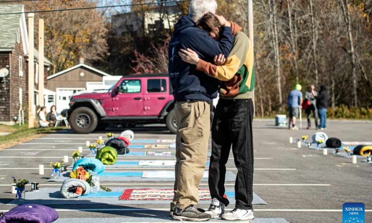 People hug with each other in front of a memorial when mourning the Lewiston Shooting victims in Lewiston, Maine, the United States on Oct. 25, 2024. This Friday marks the one year anniversary of the mass shooting in Lewison back in 2023. As many as 18 people were killed and 13 injured in the mass shooting. (Photo: Xinhua)