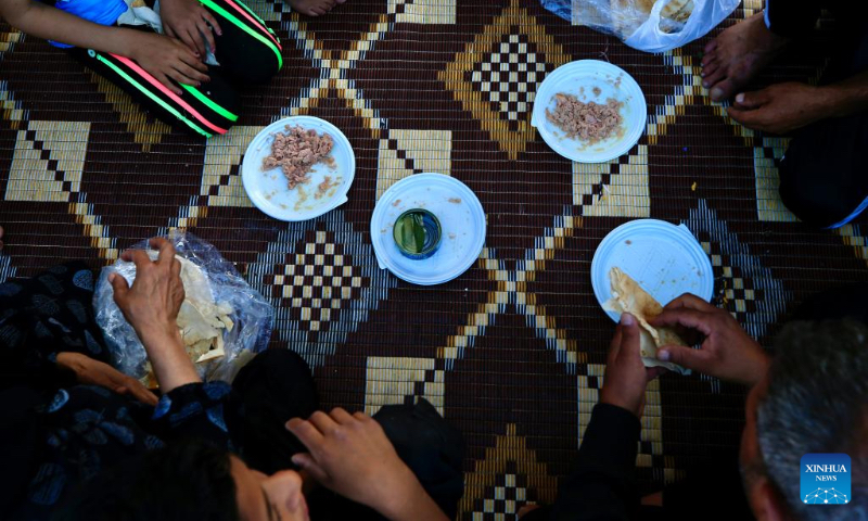 Displaced people have a meal as they live at a parking lot in Sidon, Lebanon on Oct. 3, 2024. (Photo by Ali Hashisho/Xinhua)