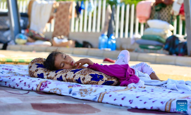 A displaced girl sleeps at a parking lot in Sidon, Lebanon on Oct. 3, 2024. (Photo by Ali Hashisho/Xinhua)