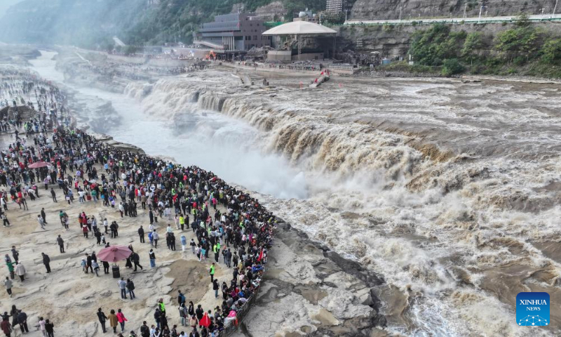 An aerial drone photo taken on Oct. 4, 2024 shows tourists visiting the Hukou Waterfall on the Yellow River, on the border area between north China's Shanxi and northwest China's Shaanxi provinces. (Xinhua/Chen Yehua)