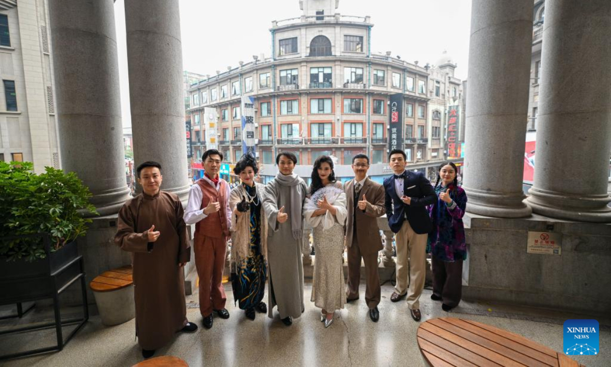 Performing staff of Tianjin People's Art Theater pose for a group photo against the background of the former Huizhong Hotel in north China's Tianjin, Oct. 26, 2024. The Chinese classic drama 