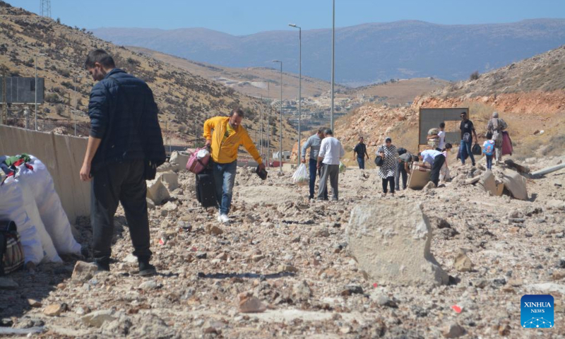 Displaced people from Lebanon cross a destroyed road caused by an Israeli airstrike near the Masnaa Border Crossing, Lebanon, Oct. 4, 2024. The Syrian Foreign Ministry denounced an Israeli airstrike on the Syria-Lebanon border on Friday, accusing Israel of targeting civilians and vital infrastructure in its ongoing campaign of aggression. According to the ministry, the airstrike hit the Jdeidat Yabous crossing, also known as the Masnaa crossing in Lebanon, a key transit route used by tens of thousands of Lebanese refugees and Syrian citizens fleeing the Israeli assault in Lebanon. (Photo by Taher Abu Hamdan/Xinhua)