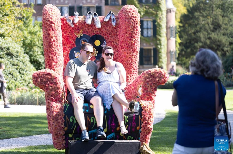 People pose for photos in an armchair decorated with dahlias at the garden of Keukenhof Castle during the Keukenhof Dahlia Days event in Lisse, the Netherlands, Sept. 7, 2024. The annual event is held here from Sept 6 to 8. Photo: Xinhua