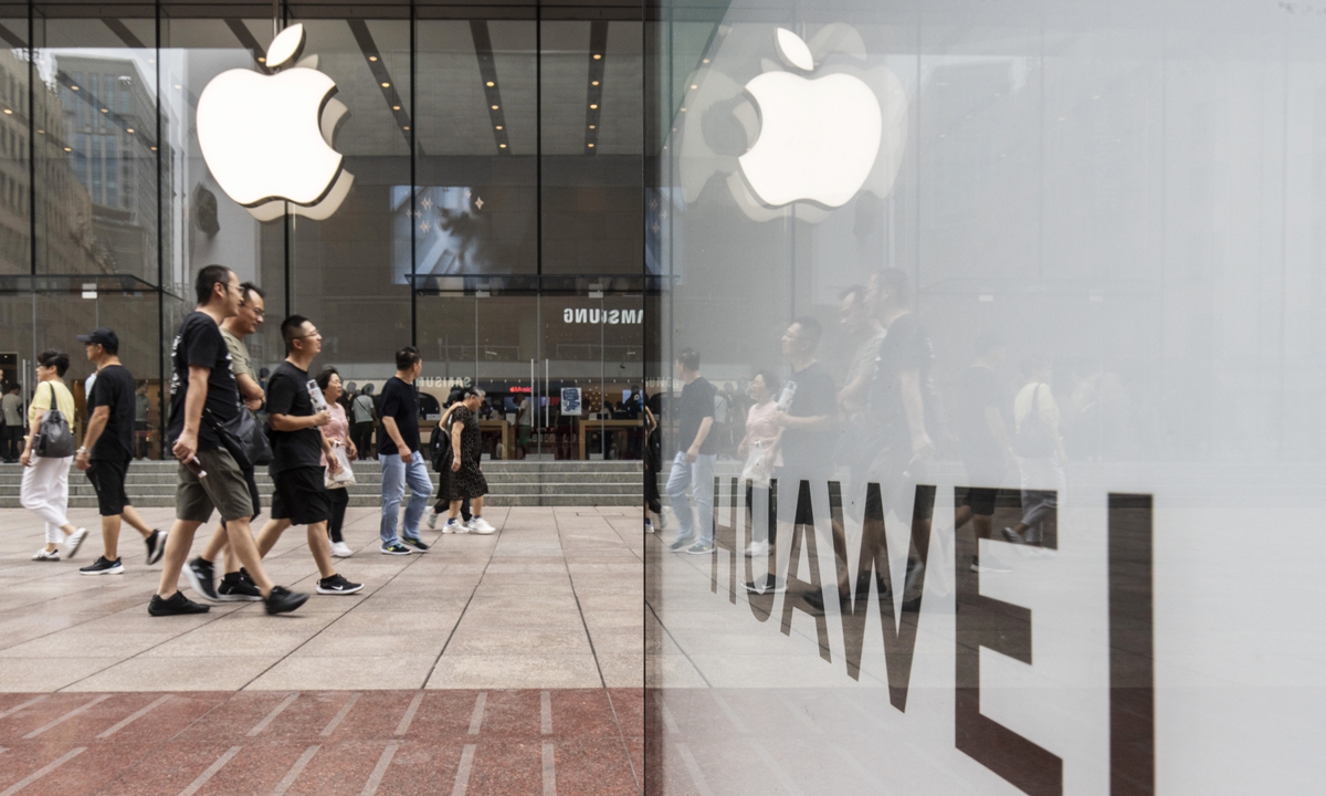 An advertisement board for Chinese tech giant Huawei reflects the Apple logo across from an Apple store in Shanghai on September 10, 2024, the day when Huawei launched its new tri-foldable smartphone Mate XT just hours after Apple unveiled its latest iPhone 16. Photo: VCG