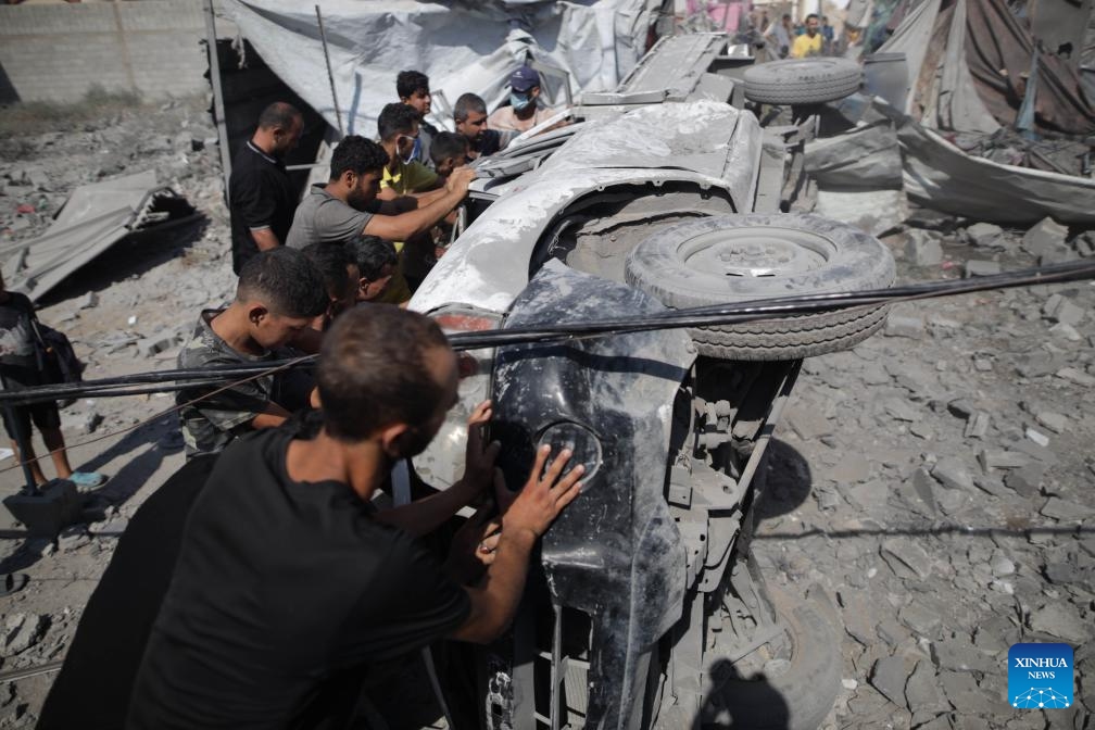 People try to move a destroyed vehicle in the Al-Bureij refugee camp, central Gaza Strip, on Sept. 10, 2024. Palestinian security and medical sources on Tuesday reported that Israeli warplanes had targeted the al-Farouk Mosque and the youth club in the Al-Bureij refugee camp. Medical sources told Xinhua that the airstrike killed one person and injured 10 others, who were taken to the hospital with varying degrees of injuries. (Photo: Xinhua)