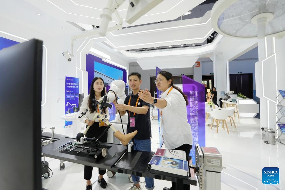 A journalist (C) watches a surgical operation robot at the China National Convention Center in Beijing, capital of China, Sept. 11, 2024. Themed Global Services, Shared Prosperity, the 2024 China International Fair for Trade in Services (CIFTIS) will be held from Sept. 12 to 16 at the China National Convention Center and the Shougang Park in Beijing. (Photo: Xinhua)