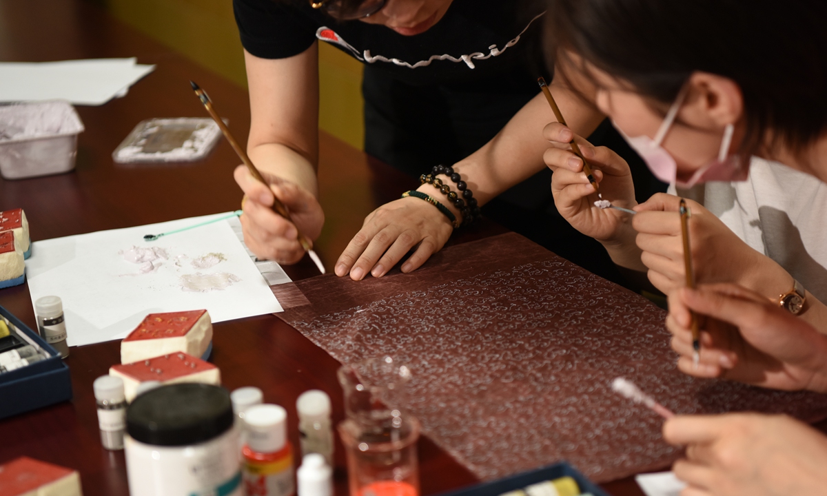 Yang Jiyuan, a restorer of ancient silk textile, and her apprentices study the details of the drawings on a Western Han Dynasty robe. Photo: Courtesy of Nanjing Yunjin Research Institute