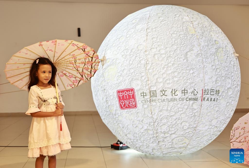 A Moroccan girl poses for photos with a moon-shaped installation before the opening of a Mid-Autumn Festival gala evening in Rabat, capital of Morocco, Sept. 10, 2024. A gala evening to celebrate the upcoming Mid-Autumn Festival was held here on Tuesday, drawing more than 400 spectators entranced by performances from Chinese artists. (Photo: Xinhua)