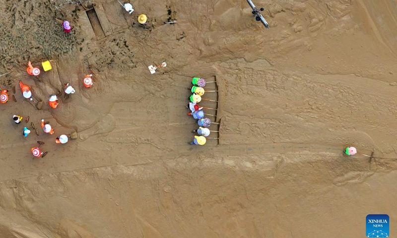 An aerial drone photo taken on Sept. 15, 2024 shows workers clearing silt at the riverside of Yongjiang River in Nanning, south China's Guangxi Zhuang Autonomous Region. Nanning has undergone the most severe flood situation since 2001 after Typhoon Yagi passed by the region on Sept. 12. (Xinhua/Huang Xiaobang)

