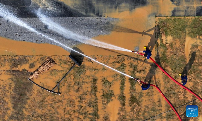 An aerial drone photo taken on Sept. 15, 2024 shows workers clearing silt at the riverside of Yongjiang River in Nanning, south China's Guangxi Zhuang Autonomous Region. Nanning has undergone the most severe flood situation since 2001 after Typhoon Yagi passed by the region on Sept. 12. (Photo: Xinhua)