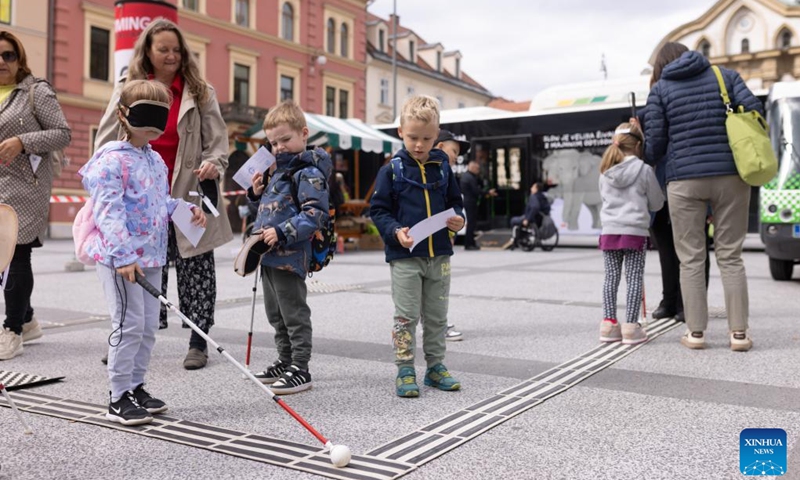 A girl tries to walk with the help of a walking stick for blind people during the European Mobility Week in Ljubljana, Slovenia, on Sept. 16, 2024. Many Slovenian cities and towns hosted events promoting sustainable transport options to mark the European Mobility Week on Monday. (Photo: Xinhua)