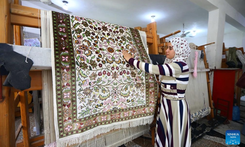 A woman shows a silk-weaved carpet at Nagaa Awni village in Beheira governorate, Egypt, on Sept. 7, 2024. Nagaa Awni, located in Beheira governorate about 200 km from Cairo, used to be a village with houses made of mud-brick and straw, relying on external aid for food and blankets. Now, thanks to about eight years of efforts by the locals through various development projects, the village has transformed into a self-sufficient area. (Photo: Xinhua)