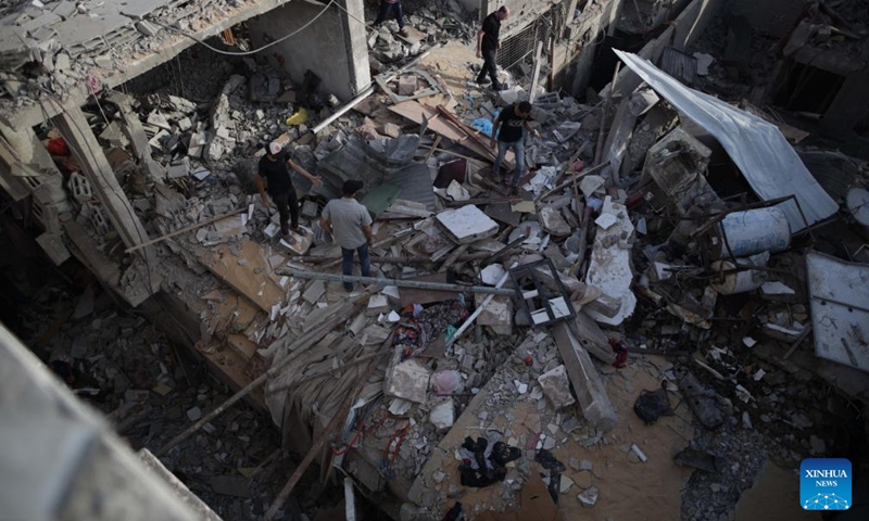 People inspect a destroyed building in the Nuseirat refugee camp, central Gaza Strip, on Sept. 16, 2024. Palestinian security sources told Xinhua on Monday that Israeli aircraft targeted a house in the Nuseirat refugee camp in the central Gaza Strip, killing at least 10.  (Photo: Xinhua)