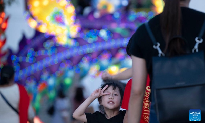 A child poses for photos in front of lanterns during the Lights by the Lake event held to celebrate the Mid-Autumn Festival in Singapore on Sept. 16, 2024. (Photo: Xinhua)