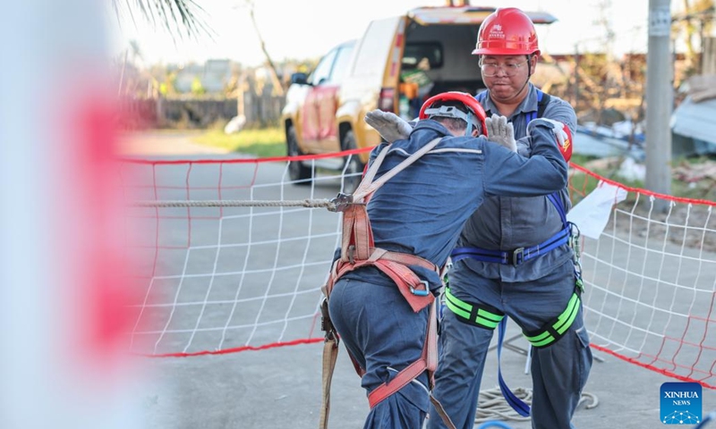 Maintenance workers Chen Hongfei (front) and Li Bing test a safety belt before climbing up an electrical wire pole in Longlou Township of Wenchang City, south China's Hainan Province, Sept. 13, 2024. Due to the impact of Super Typhoon Yagi, power facilities were damaged in different places in Hainan in the past few days. (Photo: Xinhua)